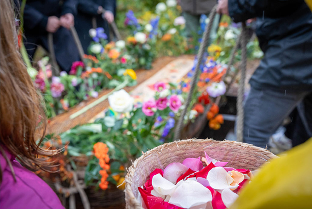 Het laten zakken van een mand met bloemenband op een natuurbegraafplaats.