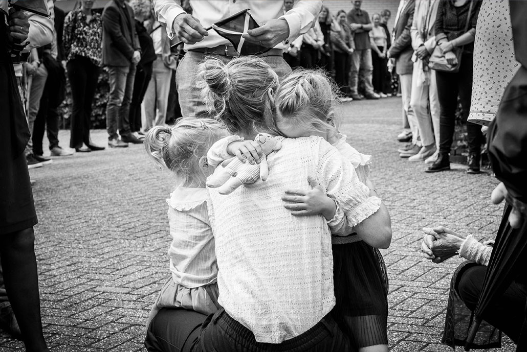 Een moeder troost haar kinderen bij het afscheid van hun oma.